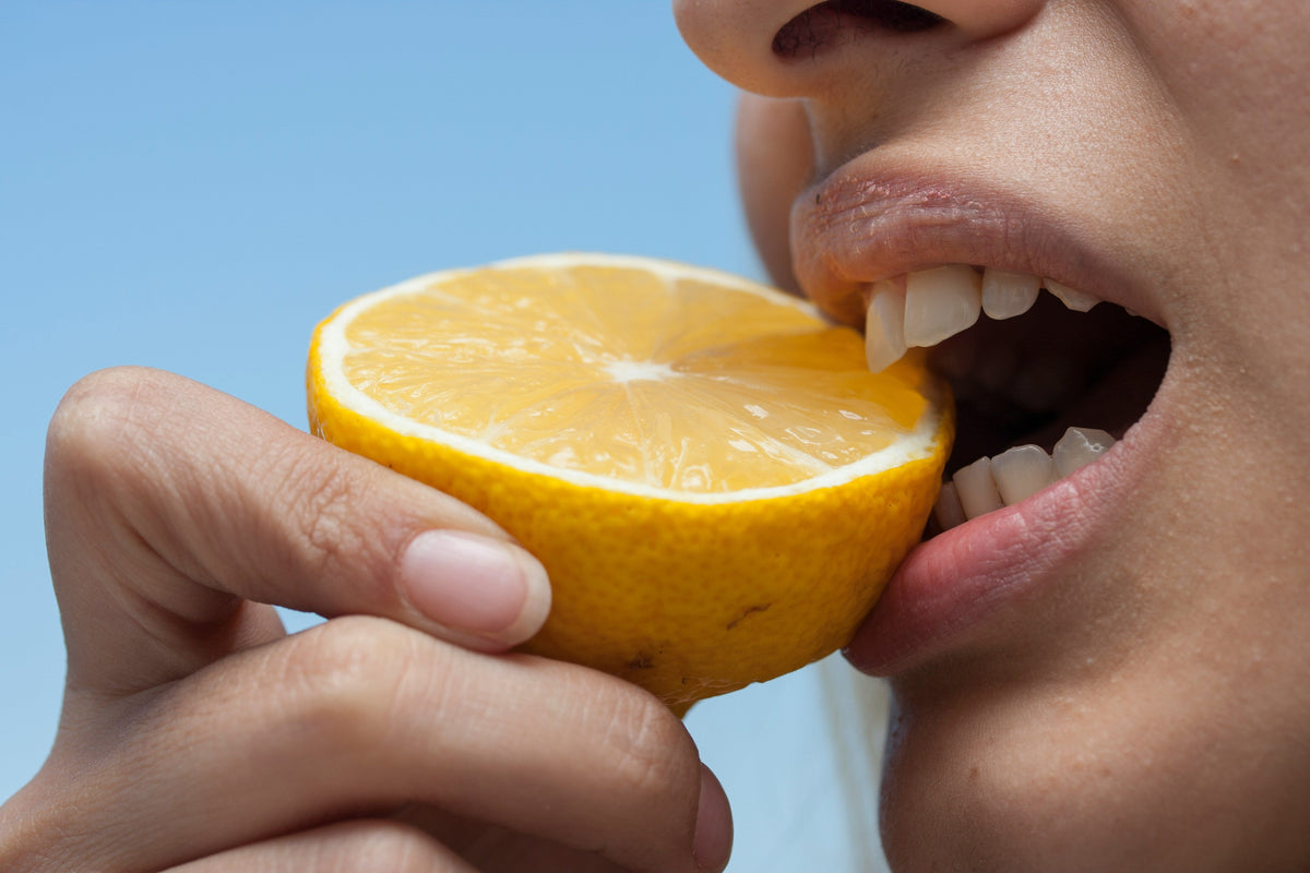 Enlighten toothpaste- woman bitting on lemon